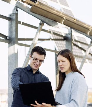 Katrin Schulte (FH Bielefeld) und Timon Jungh (Universität Bielefeld) vor einer Photovoltaikanlage, die je nach Wetterlage eine unterschiedliche Menge Energie erzeugt. Mit Künstlicher Intelligenz wollen die beiden die Einspeisung in das Stromnetz steuern. © FH Bielefeld