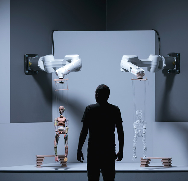  Menschen können eine schlichte Holzfigur zum Leben erwecken. Doch können das auch Maschinen? Was, wenn zur Abwechslung moderne Industrieroboter die Strippen ziehen und einer Marionette Leben einhauchen? © vog.photos