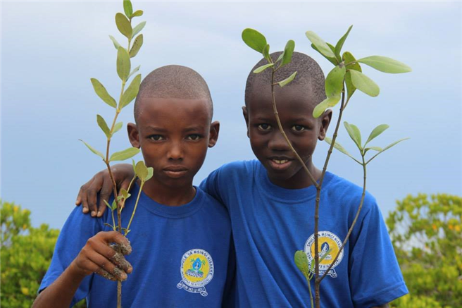 Die beiden Jungen aus Tanzania zeigen stolz ihre Bäumchen, die sie pflanzen dürfen. // Foto: Michael Rademacher/Jane Goodall Institut Deutschland