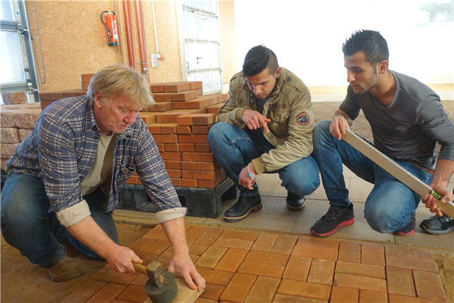 Schnuppertag bei den Landschaftsgärtnern: Ausbilder Gundolf Marré (links) befestigt das von Mohammadullah Adami (mitte) und Mohamed Kasem (rechts) verlegte Pflaster. Foto: Kottich