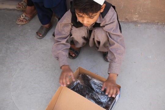 Ein Kind in Afghanistan beim Auspacken seiner Schuhspende. © shoemates GmbH, 2017