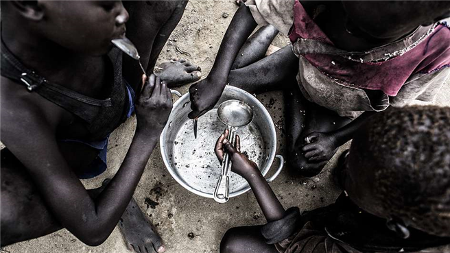 Dorfkinder in Bothoni, Südsudan essen ein Fischgericht. © Andy Spyra