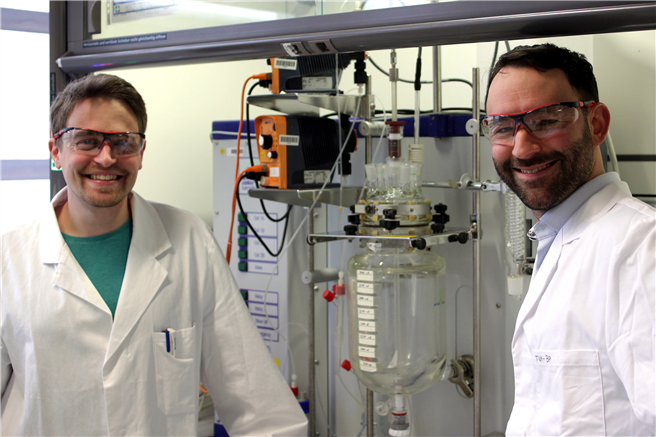 Die beiden Autoren, Paul Stockmann (links) und Dr. Van Opdenbosch, mit dem Reaktor, in dem das polymerisationsfähigen Monomer aus dem Naturstoff 3-Caren hergestellt wurde. © Prof. Cordt Zollfrank / TUM 
