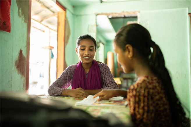 Masuma, 16, und ihre Schwester Taslima, 10, sitzen zusammen in ihrem Haus in Sylhet, Bangladesch. Masuma und ihre Schwester Taslima leben in einem ländlichen Dorf in Bangladesch. Masuma ist am Suchana-Programm beteiligt, das von UK Aid finanziert wird. Sie hat aus dem Programm Hühner und Samen erhalten, damit ihre Familie nahrhaftes Essen essen kann. Sie züchtet die Hühner und verkauft die Eier. Mit dem Geld bezahlt sie für lebensnotwendige Dinge wie Nahrung, Medizin und die Ausbildung ihrer Schwester. Sie besucht auch eine Suchana-Gruppe für heranwachsende Mädchen im Dorf, wo sie über Ernährung und andere wichtige Themen lernt und wo sie und andere Mädchen im Teenageralter ihr Selbstvertrauen und ihre Unabhängigkeit entwickeln. In der Vergangenheit hatten die Mädchen im Dorf nicht viel Freiheit und Unabhängigkeit, aber Masuma sagt, dass sich die Meinung der Menschen darüber, was Mädchen tun können und sollten, ändert, und sie hofft, dass sich dies weiter verbessert. © tom merilion/Rettet die Kinder