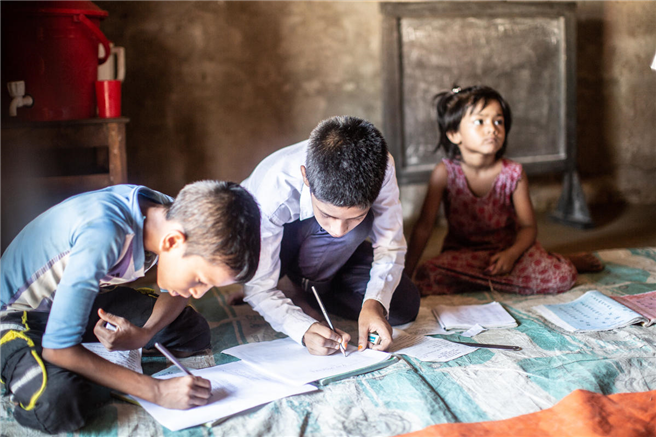 Shojib, 11, Rumis jüngerer Bruder in der Gemeinschaftsschule - Sylhet, Bangladesch. Dies ist eine informelle Gemeindeschule - für Schüler, die die Regelschule abgebrochen haben oder Zeit außerhalb der Regelschule verbracht haben (oft aus armutsbedingten Gründen). Sie fungiert auch als Vorschule, die jüngere Kinder auf die Grundschule vorbereitet. Save the children bietet die technische Unterstützung, und die lokale Partnerorganisation führt das Programm mit der Unterstützung der Gemeinde durch. Save stellt auch das pädagogische Lernmaterial zur Verfügung, und obwohl es sich um einen ehrenamtlich geleiteten Dienst handelt, bezahlt Save das Stipendium für die Lehrer. © Tom Merilion/Rettet die Kinder