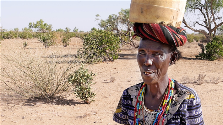 Guoshumo Lokuleu (51) ist jeden Tag viele Stunden unterwegs, um ihre Familie mit Wasser zu versorgen. 10 Liter passen in den Kanister, den sie auf dem Kopf trägt. © Hoffnungszeichen | Sign of Hope e.V.